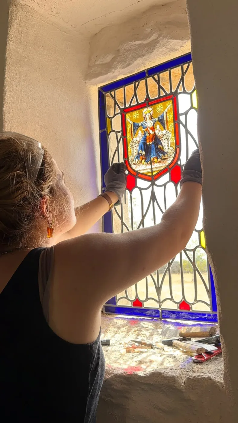 Apolline Pierron pose le vitrail au blason dans la baie de la chapelle Sainte-Anne